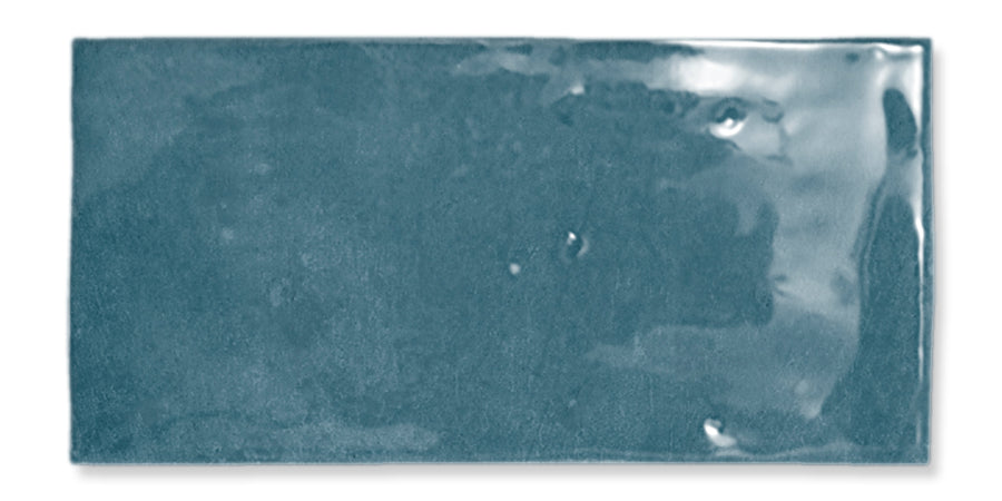 The Fez 2.5x5 Subway Tile is a glossy, rectangular blue glazed ceramic tile with a slightly uneven surface and subtle color variations.