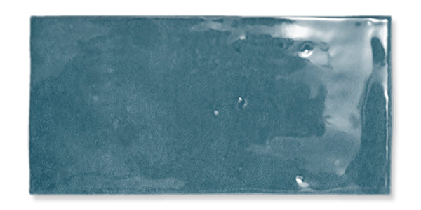 The Fez 2.5x5 Subway Tile is a glossy, rectangular blue glazed ceramic tile with a slightly uneven surface and subtle color variations.