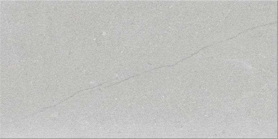 Sandwaves 12x24 Porcelain Tile features a light gray sandstone look with a subtle diagonal crack, smooth texture, scattered specks, and natural variations—ideal for contemporary design.