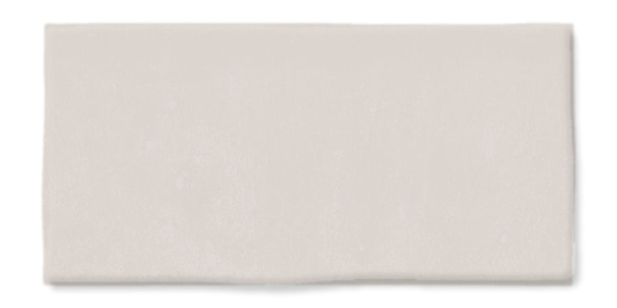 The Fez 2.5x5 Subway Tile is a rectangular, flat, light gray glazed ceramic tile with a smooth surface and slightly uneven edges, shown against a white background.